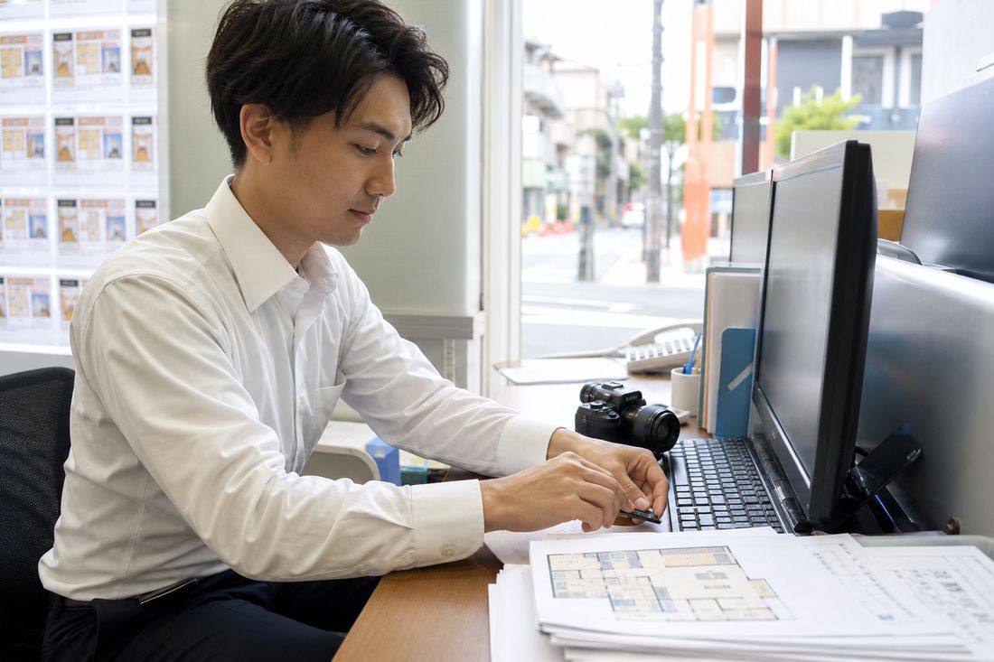 物件情報と掲載画面を見比べる事務スタッフ